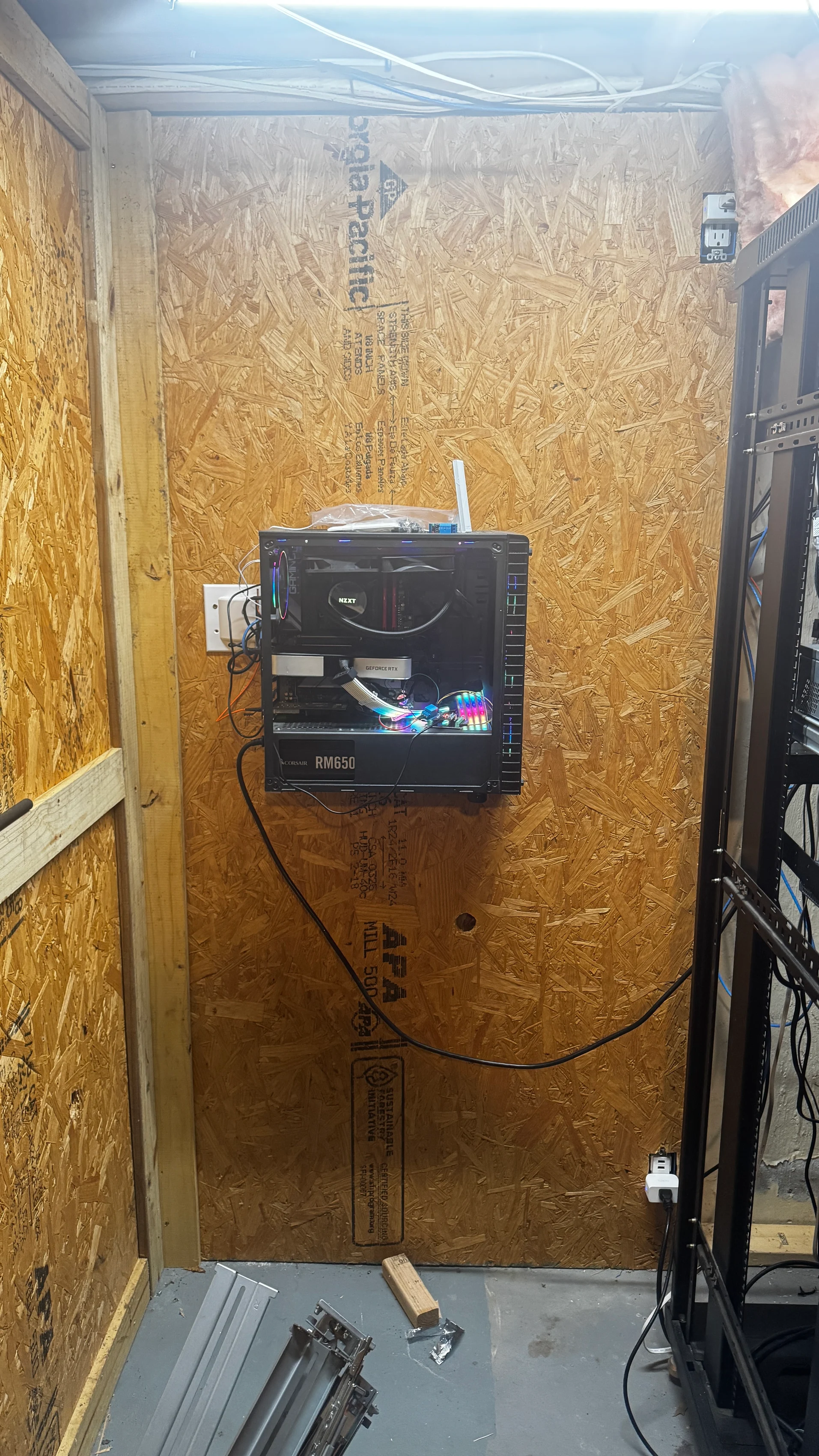 Wall-mounted open computer case beside the rack